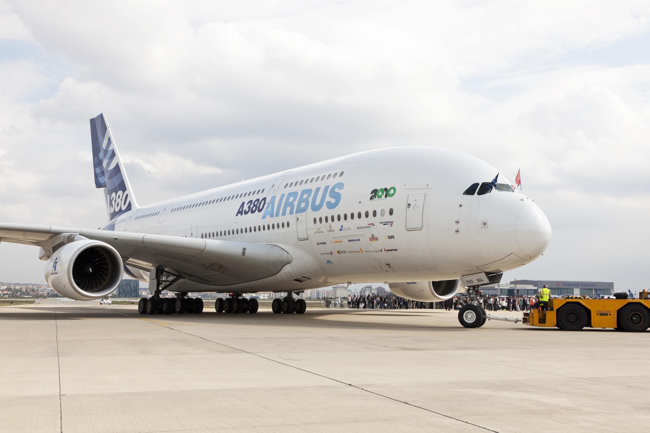 An Airbus A380 on the tarmac with aircraft observers in the background.