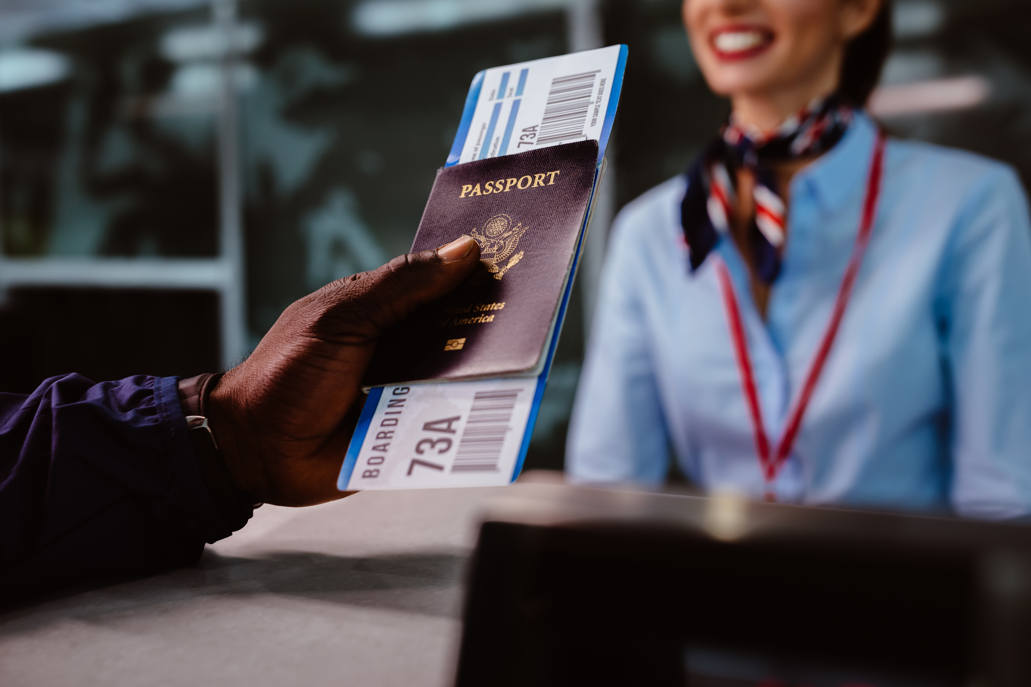 close up of a male hand holding passport and airline ticket stretching towards stewardess at counter