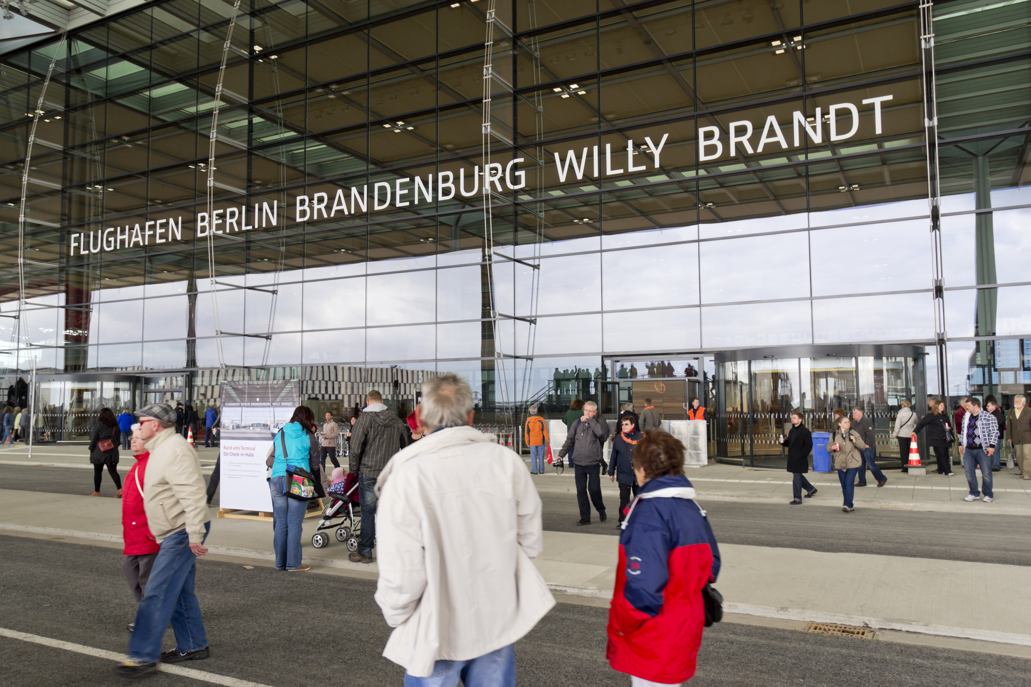 The main entrance of Berlin Brandenburg Willy Brandt Airport with many people in the foreground.