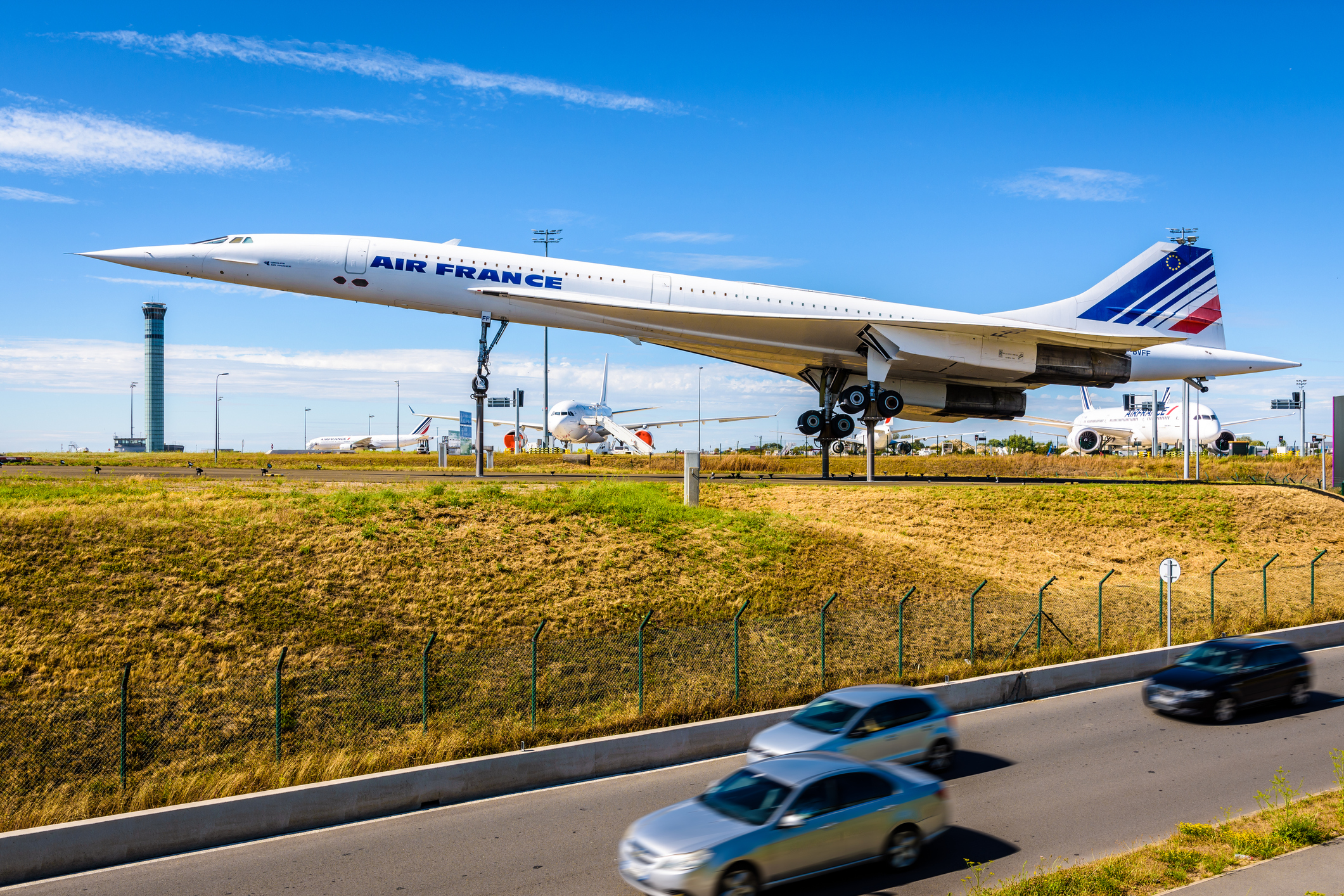 An Air France Concorde on display at Paris Charles de Gaulle Airport, with other Air France aircraft in the background.