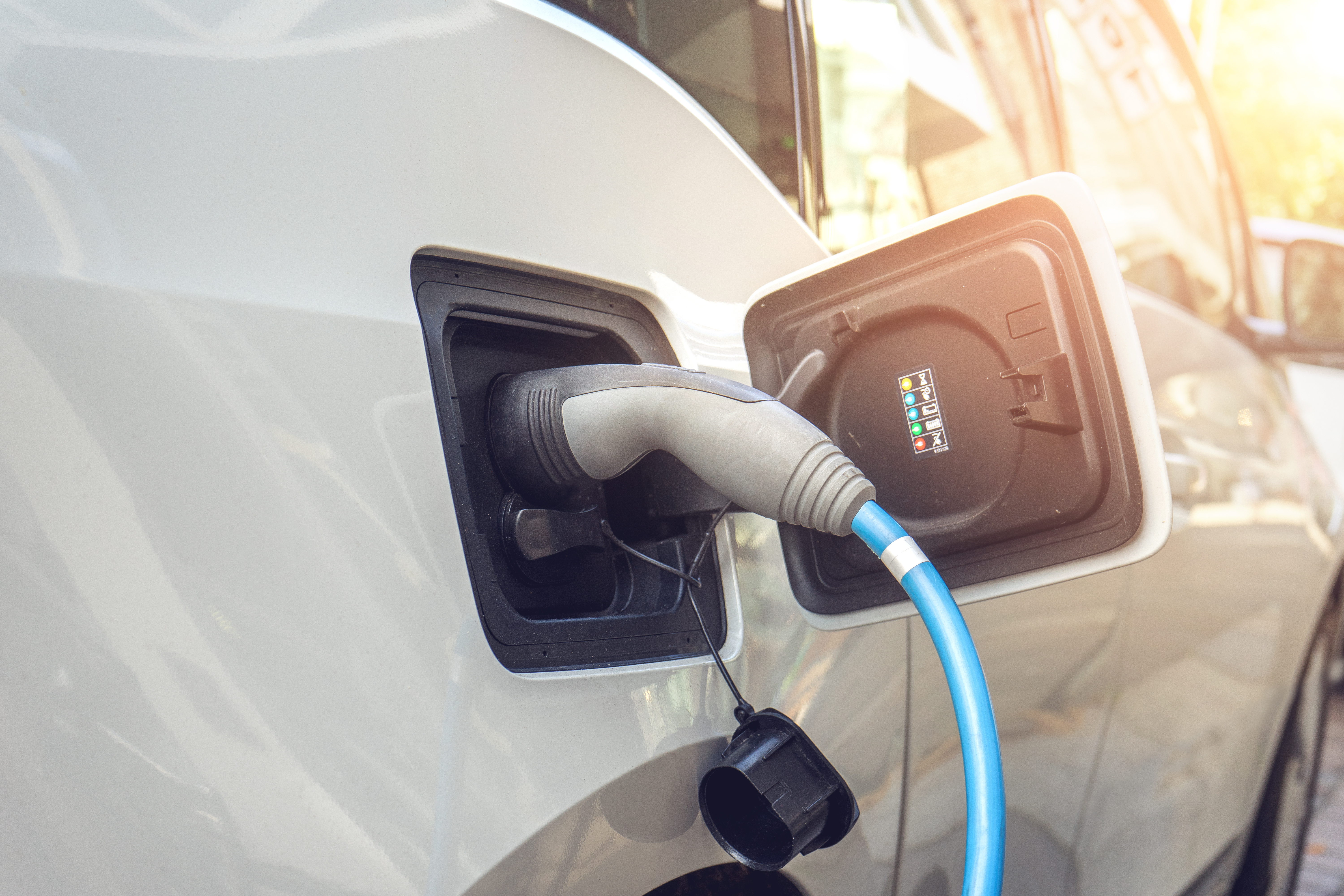 A close-up of the fuel filler opening of an electric car, a charging cable is connected.