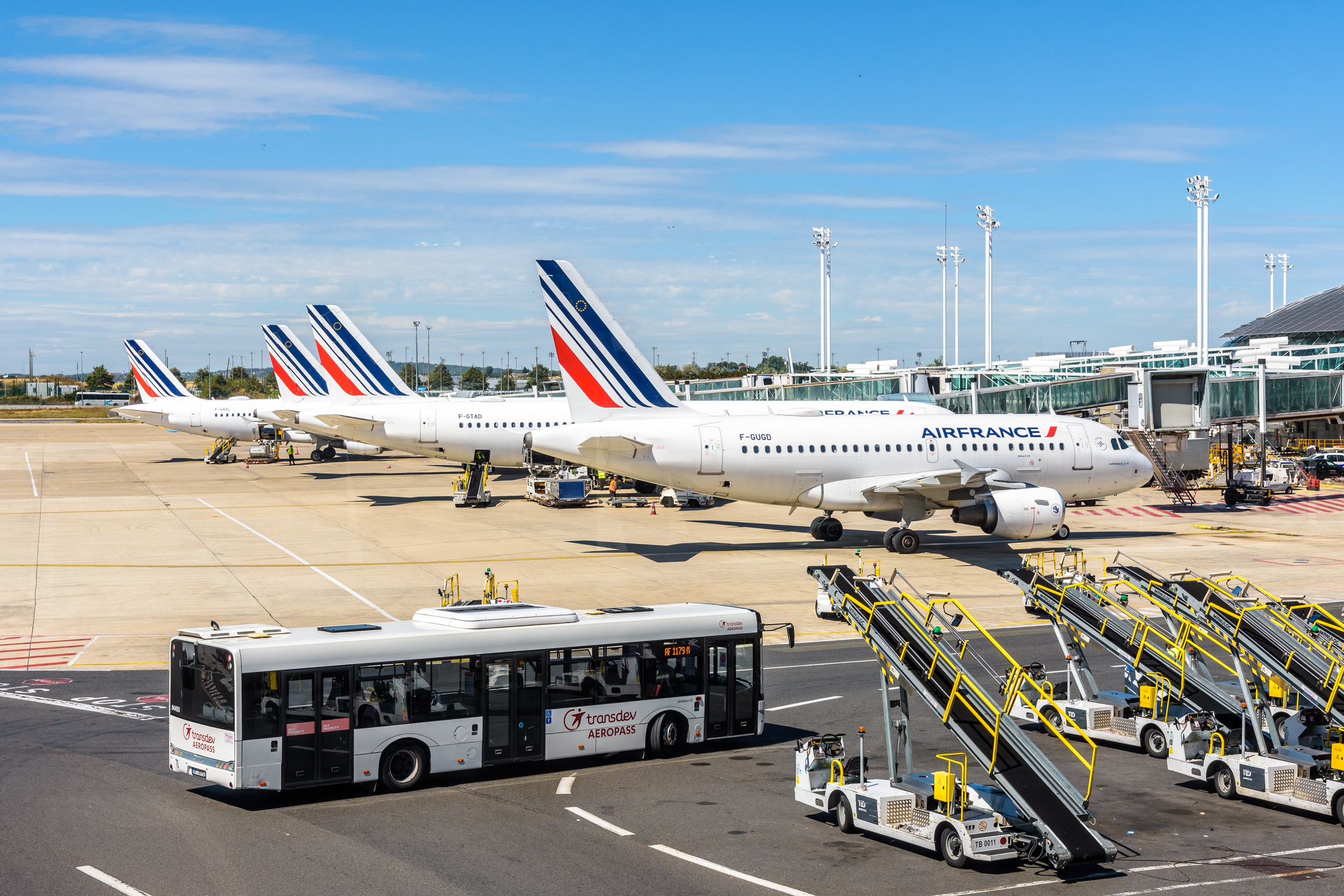 A row of Air France planes is parked side by side, in the foreground a bus brings passengers to the planes.