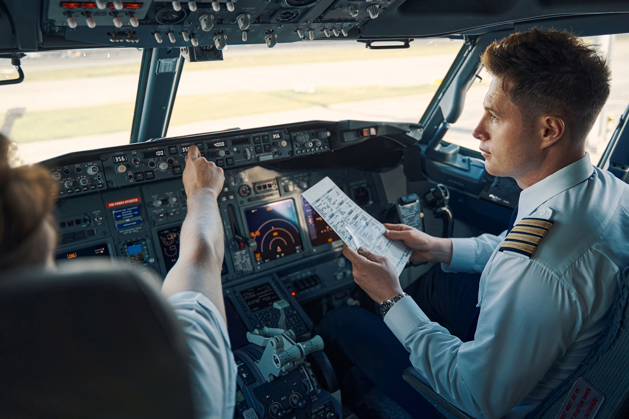 Pilots check instruments and flight information in the cockpit before take-off.