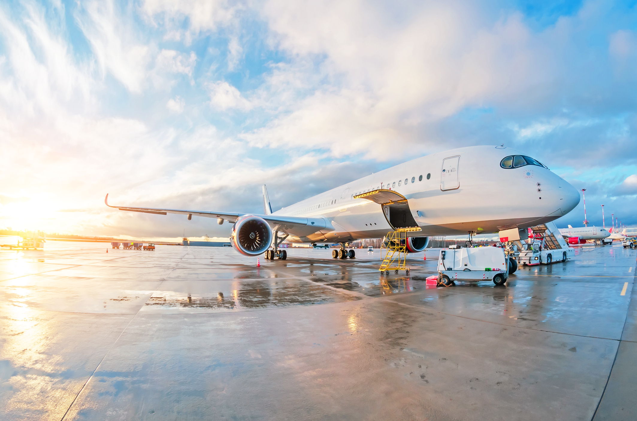 Maintenance work on parked passenger plane on wet ground at airport at sunset