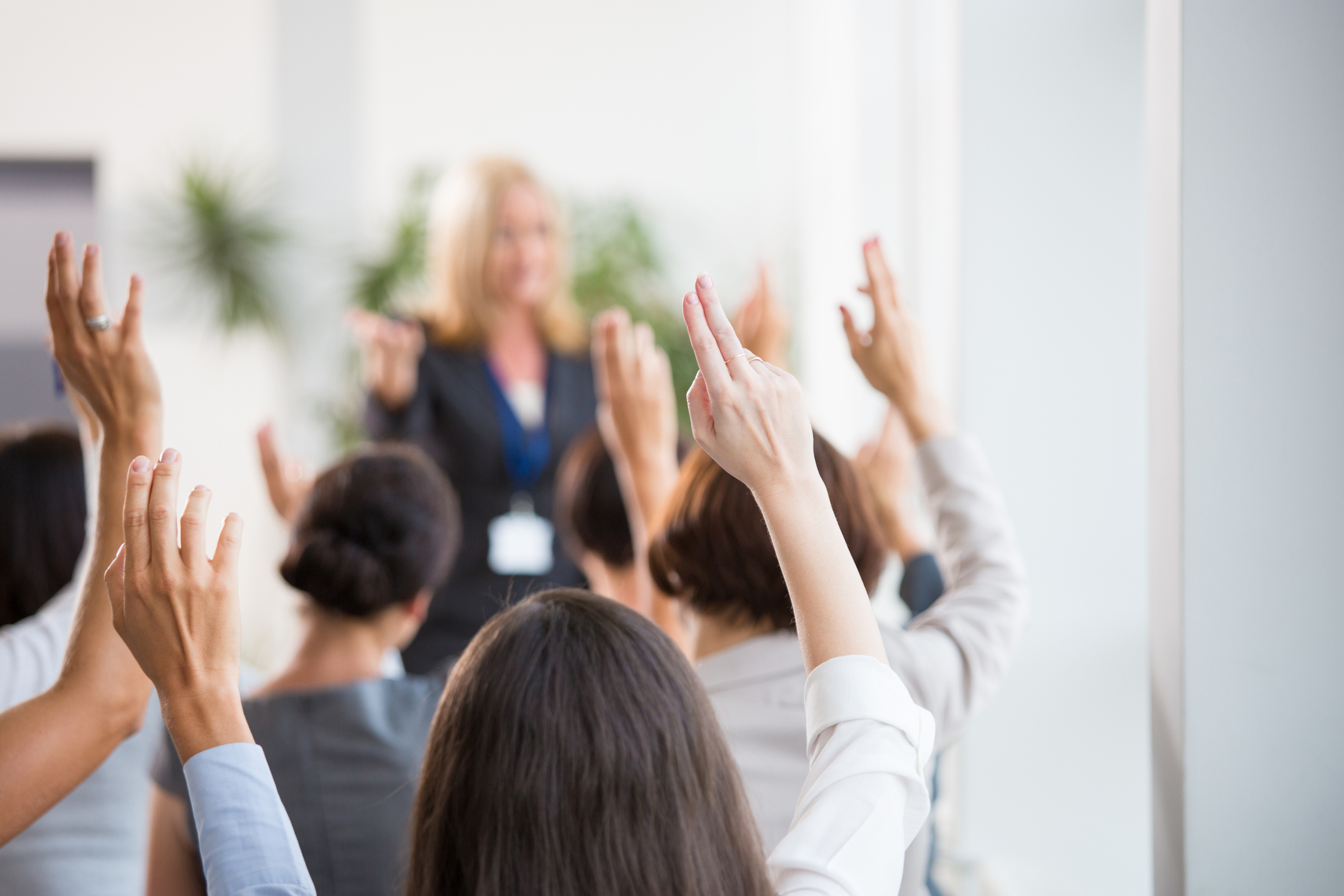 several people bidding for a certain product at an auction with their hands raised and their bodies facing the auctioneer