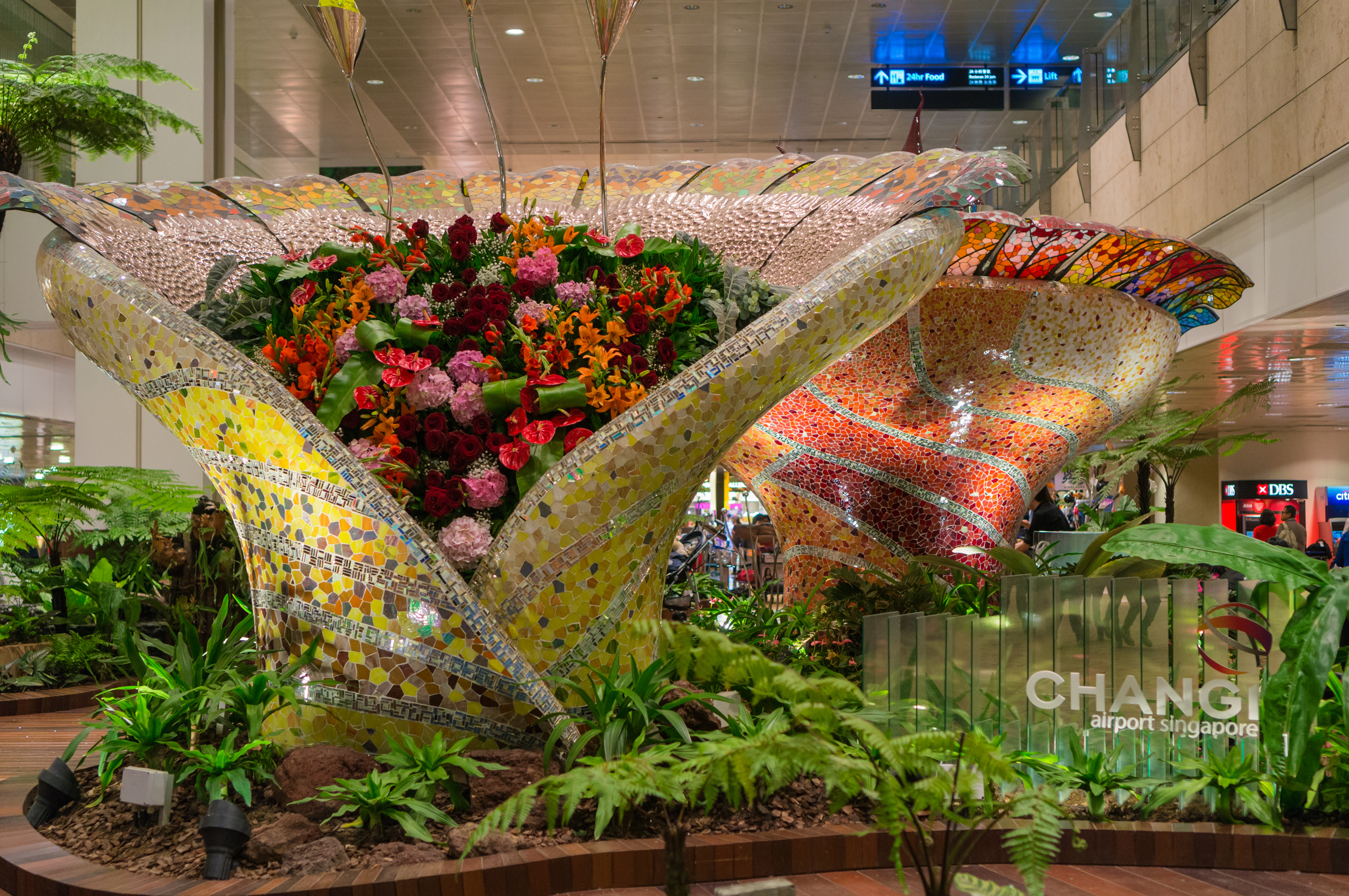 Two very large flower boxes decorated with ornate mosaics inside Changi Airport.