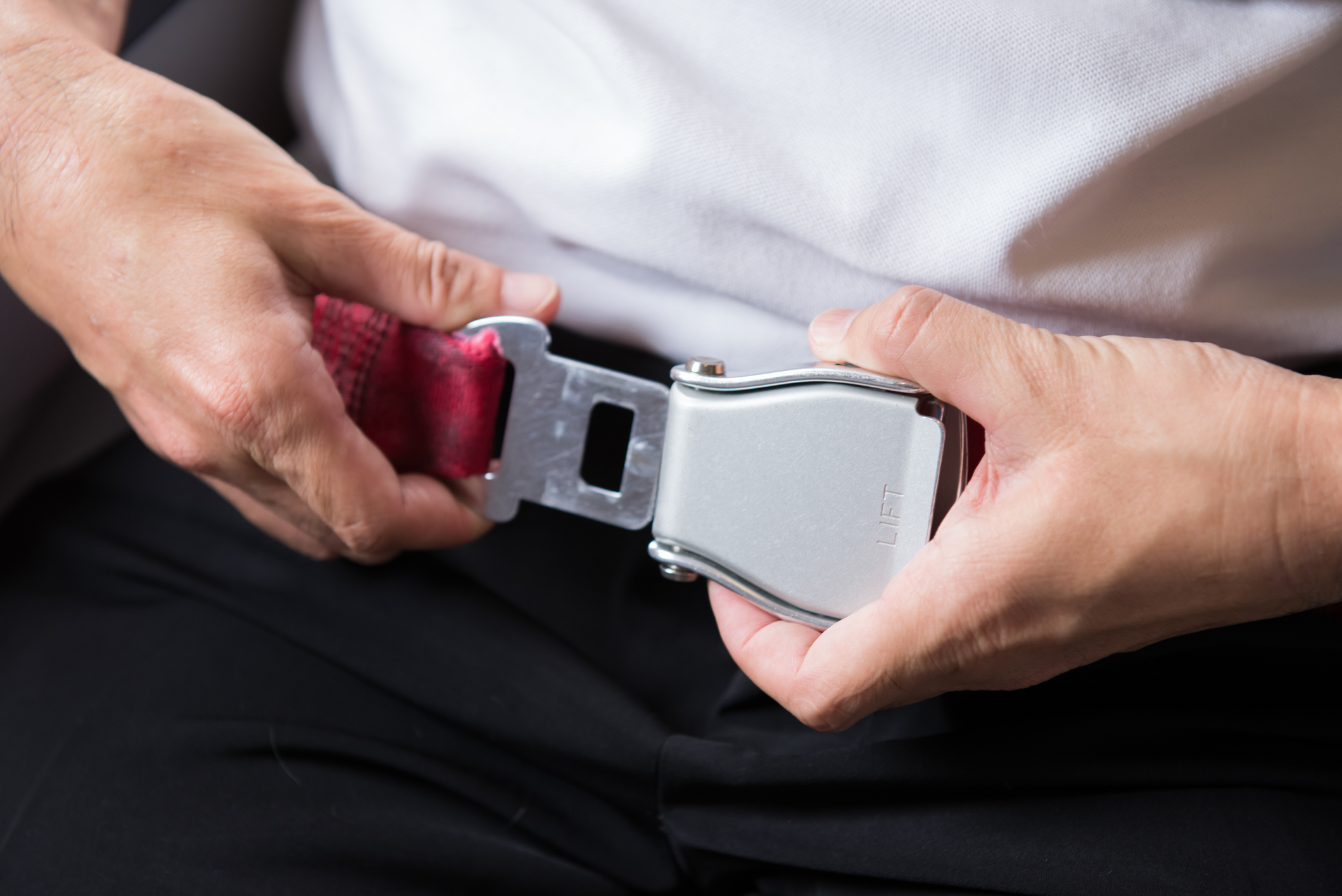 A seat belt in a plane is fastened with both hands.