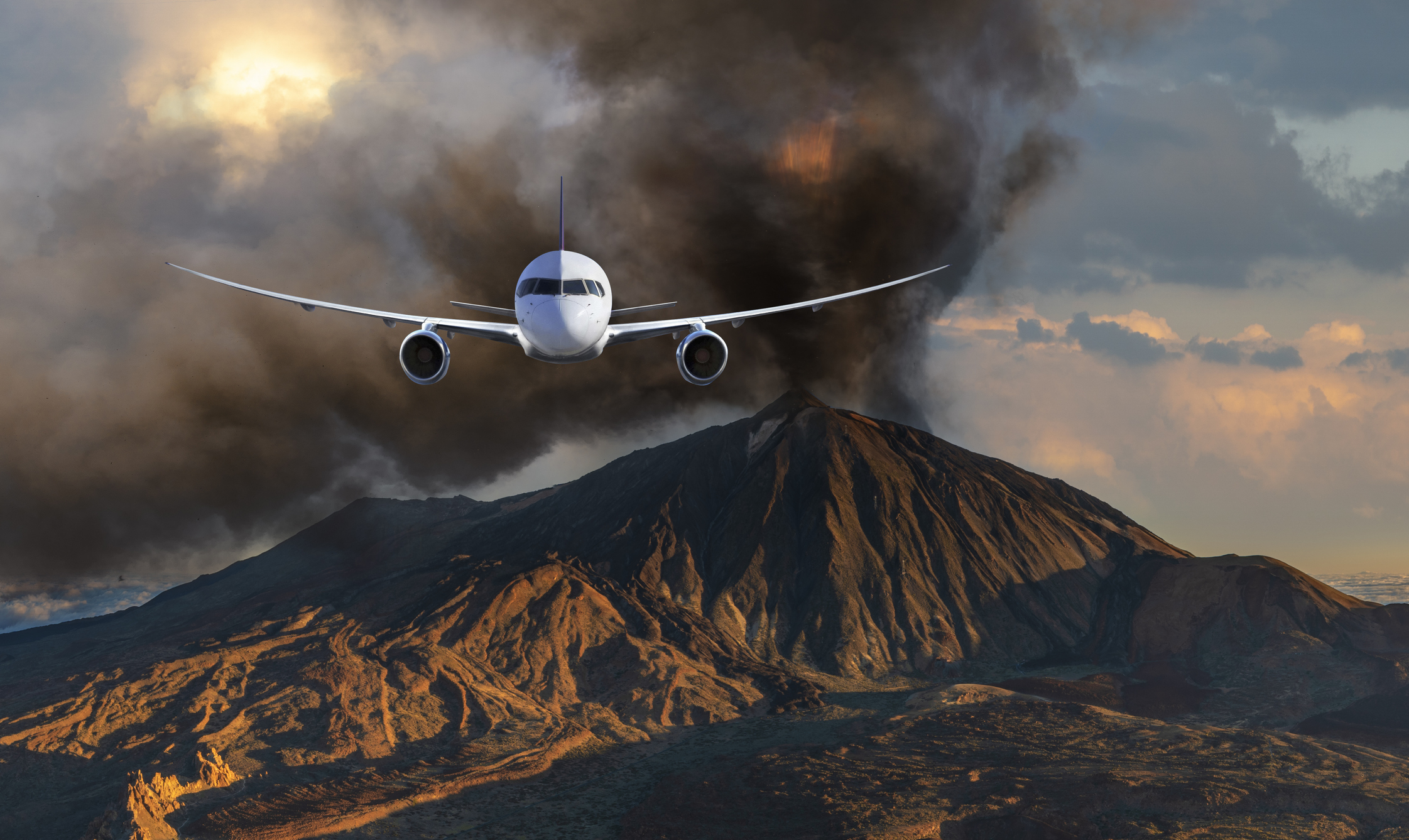 An airplane flies towards the camera, an ash cloud and volcanic landscape can be seen in the background.