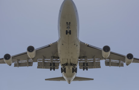A Boeing 747 from below with its landing gear extended.