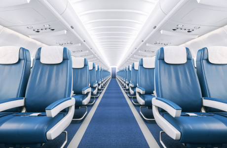 Empty aisle in completely empty airplane with blue carpet, white blanket and blue and white leather seats