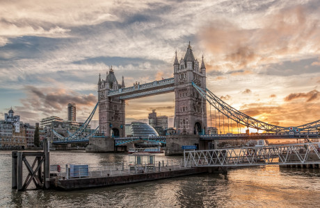Tower Bridge in London against a dramatic sunrise, a footbridge can be seen in the foreground.