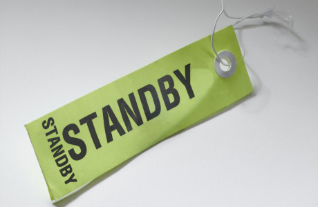 A bag tag with the inscription "STANDBY" lies on a white surface.