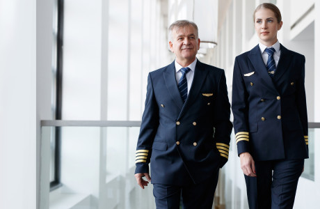 Flight attendant and young stewardess in blue uniform walk side by side from terminal to plane to prepare everything for departure.