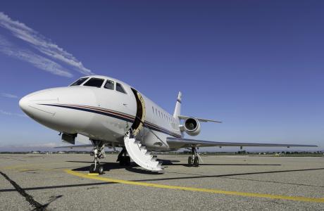A private jet stands on the tarmac with an open door.