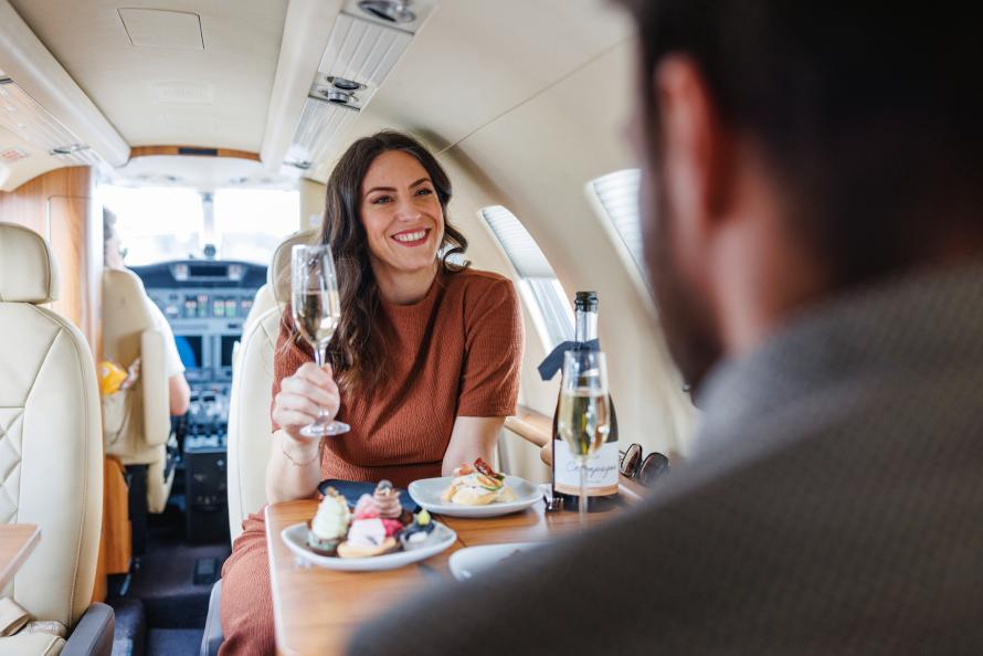 A woman in a private jet drinks champagne.